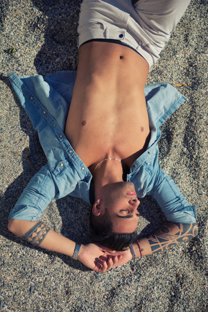 Handsome man laying on surfboard at beachの写真素材