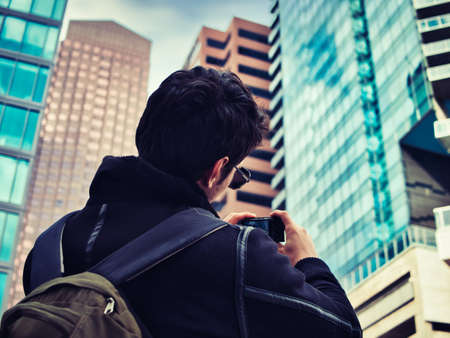 Young man taking photograph with smartphone in modern city