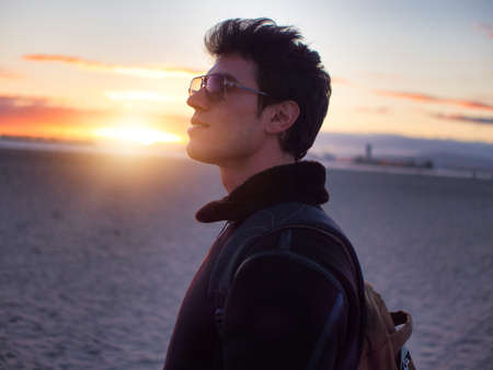 One handsome young man at the beach at sunset