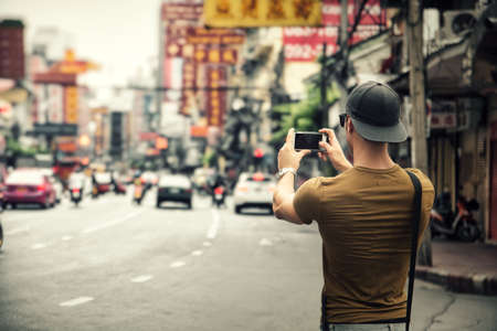 Man taking photo of city on smartphoneの写真素材