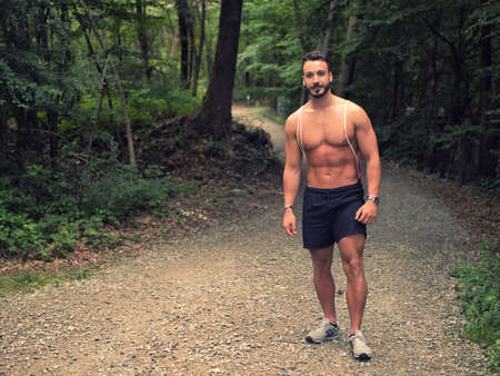 Young man shirtless outdoors hiking with backpack on shoulderの写真素材