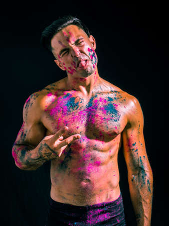 Muscular man shirtless with skin painted with Holi colorsの写真素材