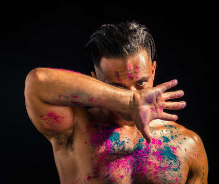 Muscular man shirtless with skin painted with Holi colorsの写真素材