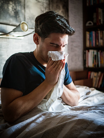 Young man blowing his nose with handkerchiefの写真素材