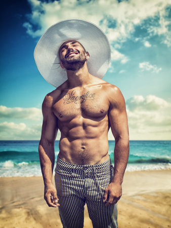 Handsome muscular young man on beach, smilingの写真素材