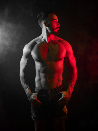 Shirtless muscular male bodybuilder in studio shot on black