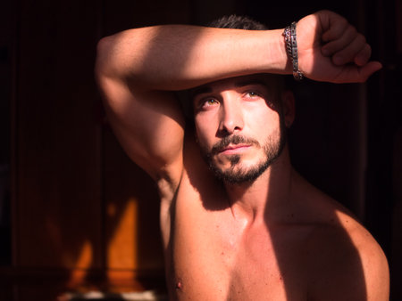 Portrait of sexy shirtless muscular man next to windowの写真素材