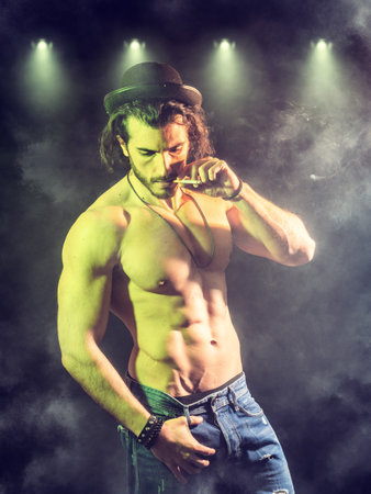 Confident, attractive shirtless muscular young man smoking cigarette