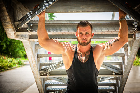 Muscular attractive athletic man in city under stairs