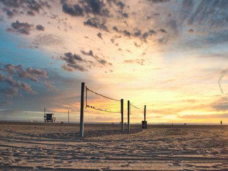 Volleyball net on empty beach under sunrise skyの写真素材