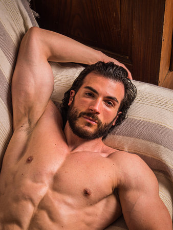 Shirtless muscular young man at home on couch