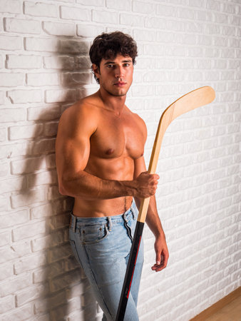 Handsome young man shirtless with hockey stick in handsの写真素材
