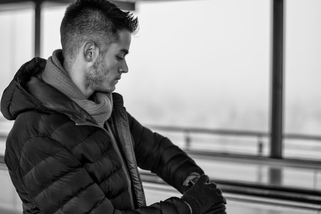 Photo of a man engrossed in his watch while sitting on a benchの写真素材