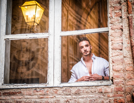 Photo of a confident man with crossed arms standing in front of a windowの写真素材