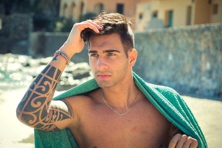 Photo of a man wearing a green towel on his shoulders by the seaの写真素材
