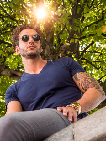 Photo of a man perched on a stone wall, enjoying the viewの写真素材