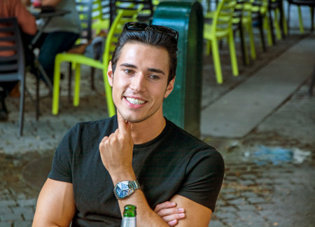 Photo of a man enjoying a cold beer at a table in a casual settingの写真素材