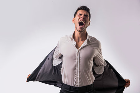 A man in a white shirt and black pants screaming with anger or frustration or desperationの写真素材