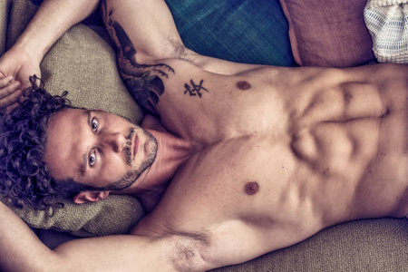 A man laying on top of a couch next to a pillowの写真素材