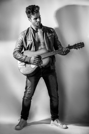 A shirtless man with an open jacket on nude torso, holding an orange guitarの写真素材