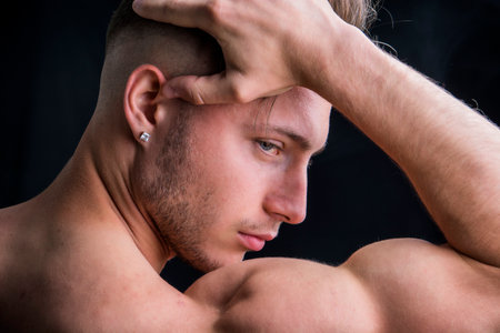 A shirtless man holding his head in his handsの写真素材