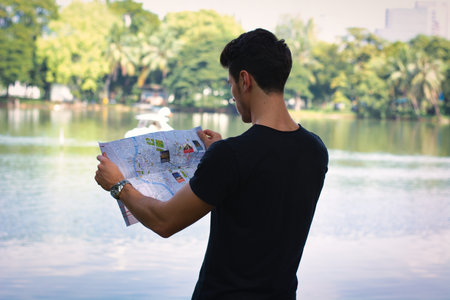 A man looking at a map in front of a lakeの写真素材