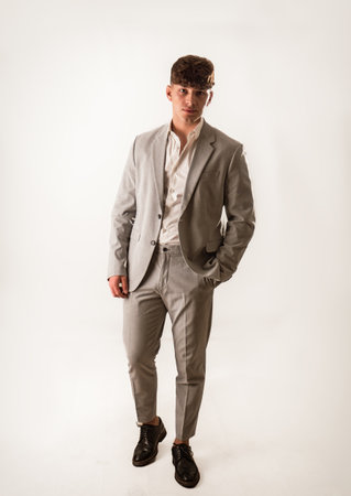 Full figure shot of handsome elegant young man with business suit, on white, looking at cameraの写真素材