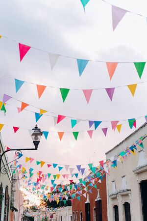 Colored flags against a pink sunset sky in a colonial Spanish town in Mexicoの写真素材