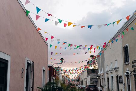 Colored flags against a pink sunset sky in a colonial Spanish town in Mexicoの写真素材