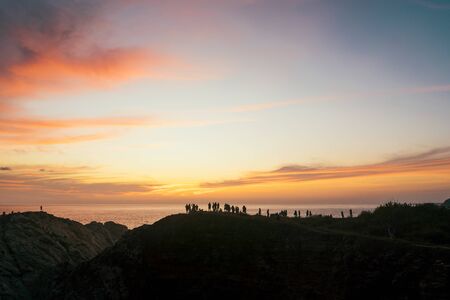 A crowd of people admire the sunset on a cliff on the Pacific Ocean in Mexicoの写真素材
