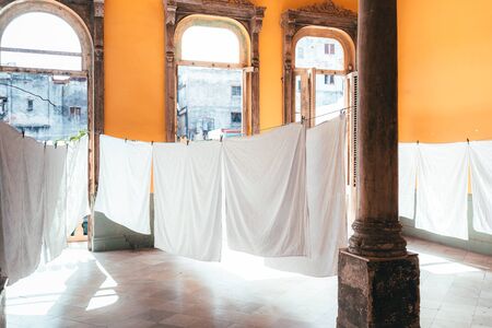 White sheets are dried on the clothesline in an old colonial yellow house in Cuba in Havana