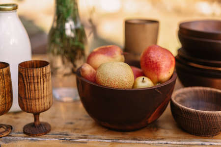 Pears lie in a wooden plate on a wooden table near to glassesの写真素材