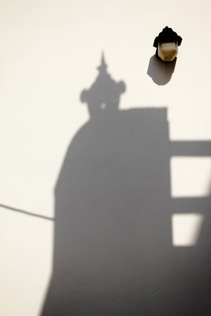 Shadow of a man in the shadow of an old house on a white wall