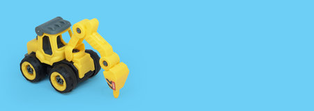 yellow plastic tractor drill toy isolated on blue background with a copy space for text or toy store...