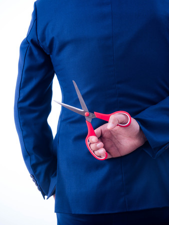 Young businessman holding scissors on the back isolated from a white background.