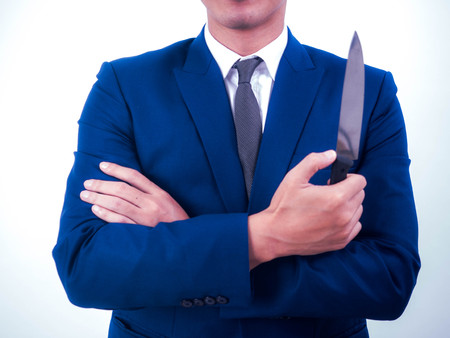 Young businessman holding knife isolated from a white background.の写真素材