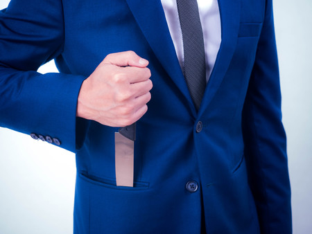 Young businessman holding knife in a suit pocket isolated from a white background.の写真素材
