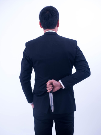 Young businessman holding knife on the back isolated from a white background.の写真素材
