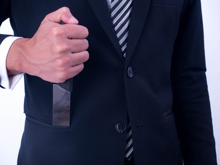Young businessman holding knife in a suit pocket isolated from a white background.の写真素材