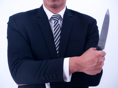 Young businessman holding knife isolated from a white background.の写真素材