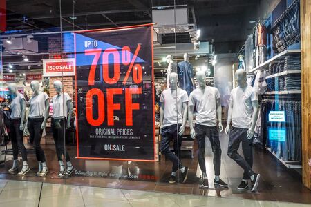 BANGKOK THAILAND, April 1, 2017: Large red Sale letters on a glass wall obstruct a view inside the popular clothing cotton on store. Sale 70% Off & Over - Final Saleのeditorial素材