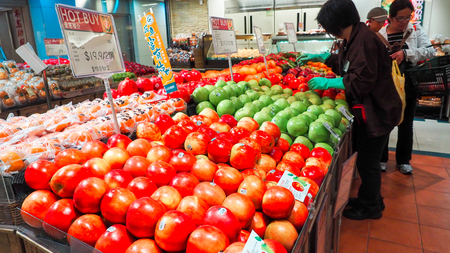 Woman selecting fresh red apples in grocery store produce department and putting it in plastic bag. Young pretty girl is choosing apples in supermarket and putting them into shop basket. Close upのeditorial素材