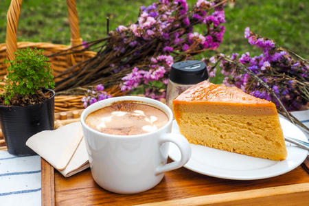Coffee mugs on a wood tray with cake and flowers.の写真素材