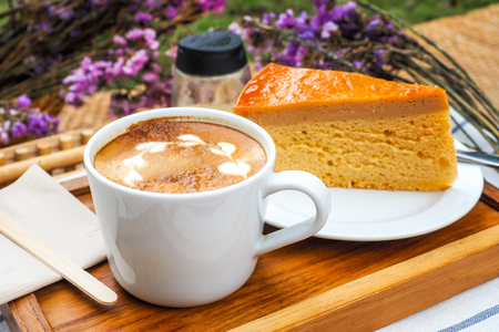Coffee mugs on a wood tray with cake and flowers.の写真素材