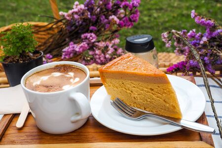 Coffee mugs on a wood tray with cake and flowers.の写真素材