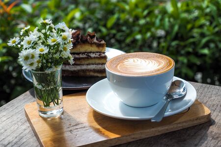 Coffee cup on a wooden table and the little flowers with cake.の写真素材