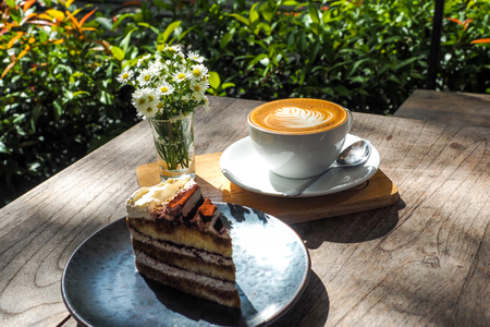 Coffee cup on a wooden table and the little flowers with cake.の写真素材