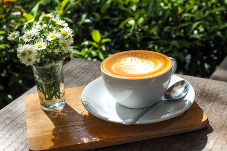Coffee cup on a wooden table and the little flowers with cake.の写真素材