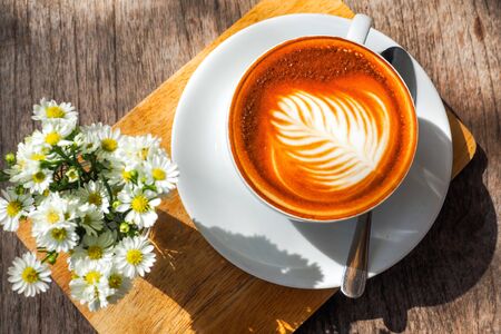 Coffee cup on a wooden table and a Little flower.の写真素材