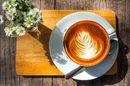 Coffee cup on a wooden table and a Little flower.の写真素材